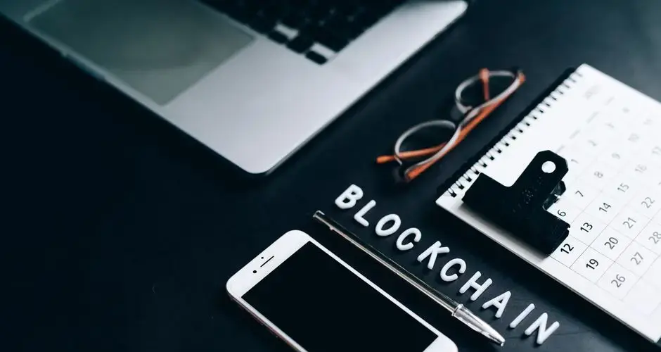 Flat lay of a modern digital workspace with blockchain theme, featuring a smartphone and calendar.