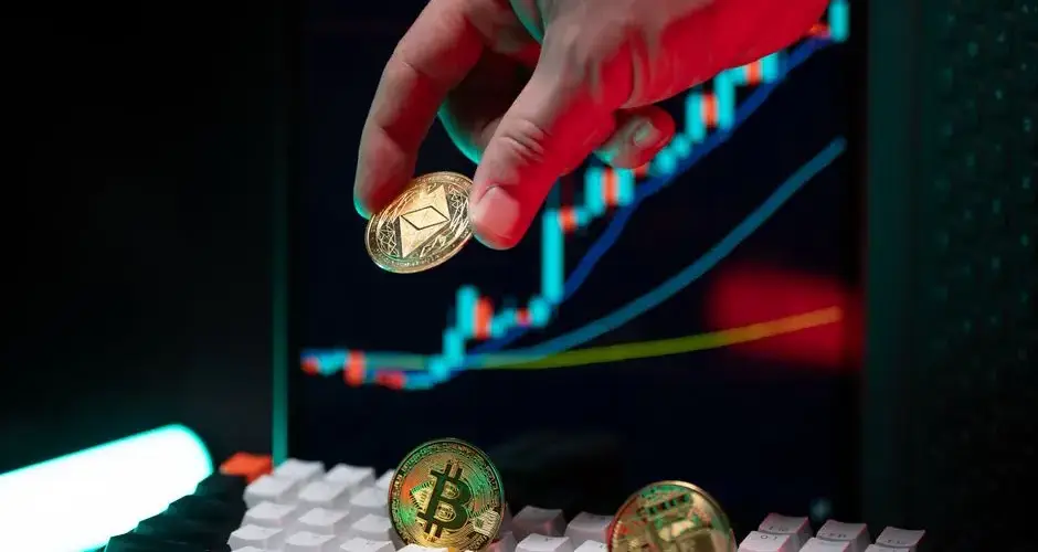 A hand holding cryptocurrency coins with a financial chart in the background, depicting market trends.