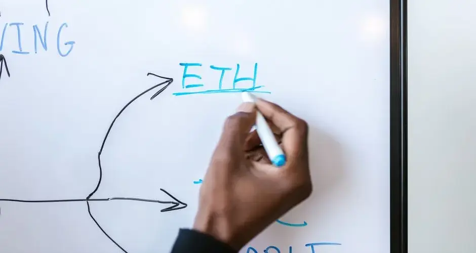 Hand writing 'ETH' on a whiteboard, highlighting Ethereum concept.