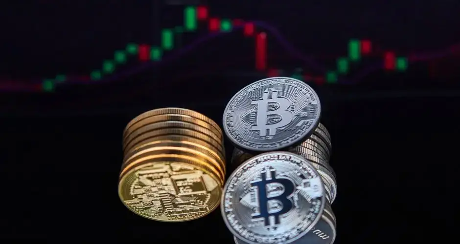 Closeup of Bitcoin coins with a market chart in the background showing financial trends.
