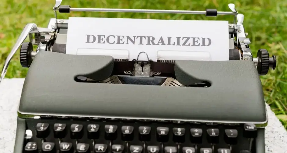 Vintage typewriter outdoors with 'Decentralized' typed paper, symbolizing old meets new in technology.