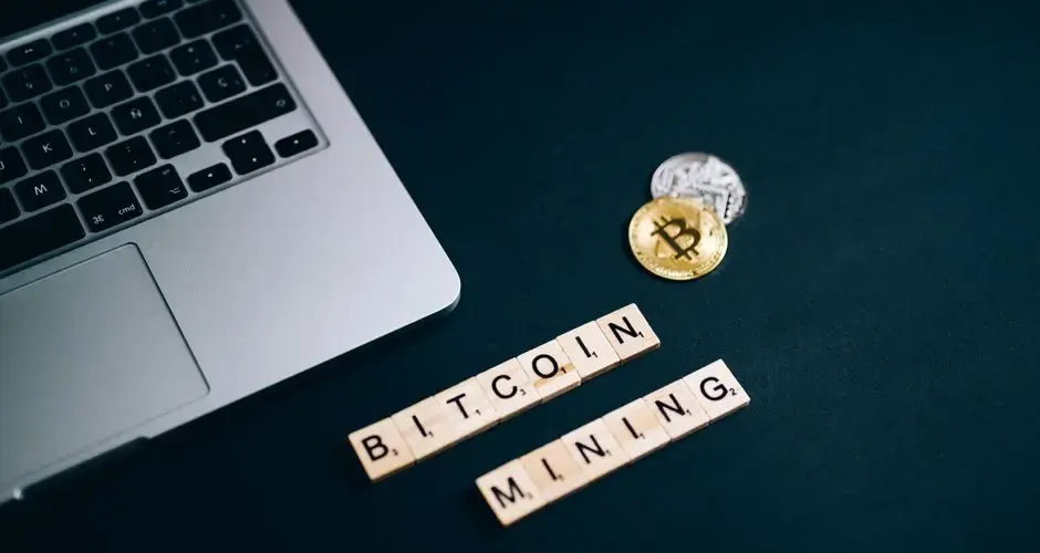 Top view of Bitcoin mining concept represented with laptop keyboard and Scrabble tiles.