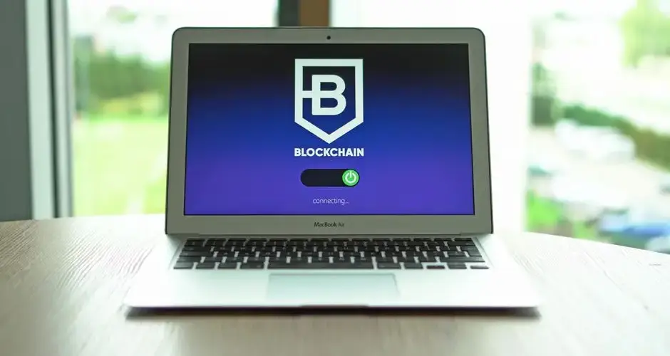 MacBook Air displaying a blockchain concept screen in a bright indoor setting.