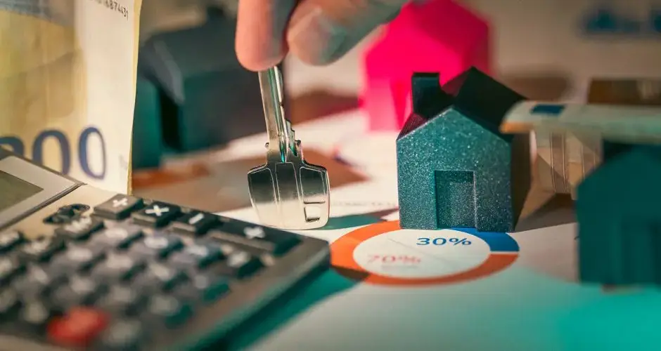 A close-up of real estate financial planning with keys, calculator, and money.