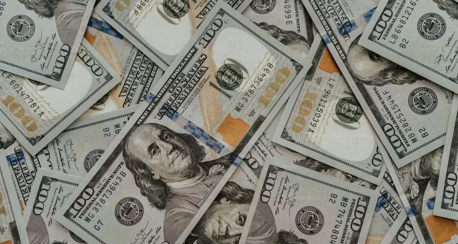 Close-up of American 100 dollar bills scattered, highlighting wealth and currency concepts.