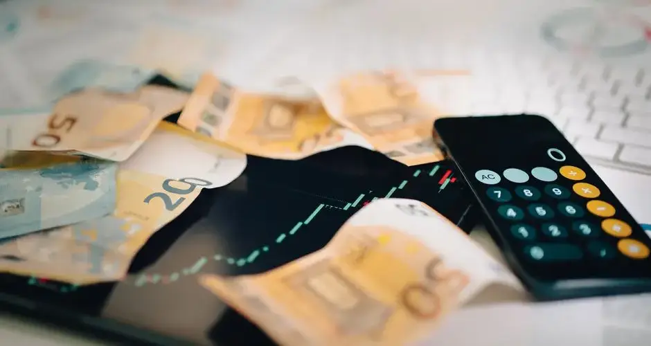 Euro banknotes scattered on a trading chart with a calculator, symbolizing finance and analysis.