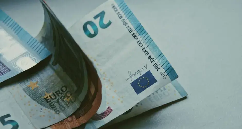 Detailed close-up of Euro banknotes on a white surface, focusing on currency design.