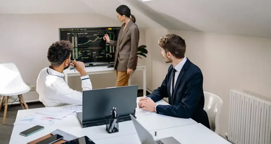 Professionals discussing stock market trends with charts in an office setting.