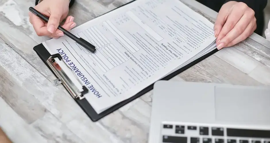 Close-up of hands reviewing a home insurance policy, emphasizing professionalism and finance.