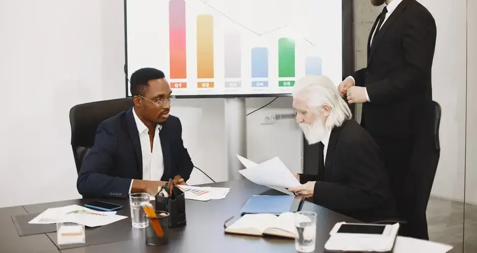 Three businessmen discussing financial data in a modern office setting with charts.