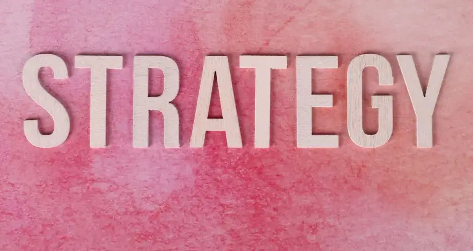Wooden letters spelling 'Strategy' on a pink textured background.