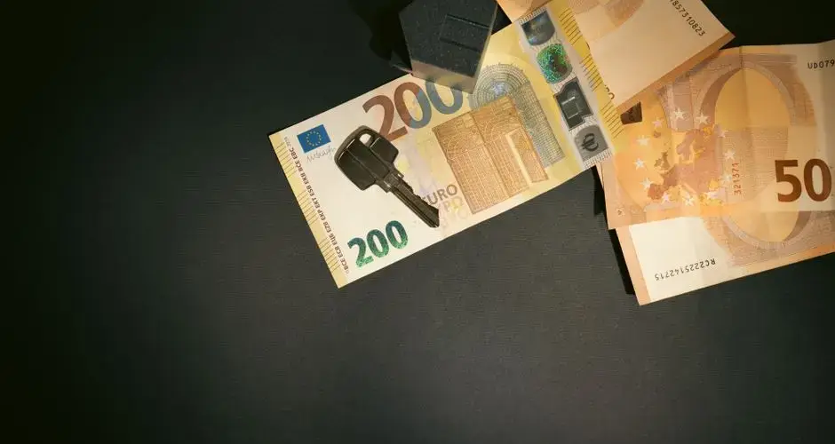 Flat lay of a house key on Euro bills representing real estate investment and finance.