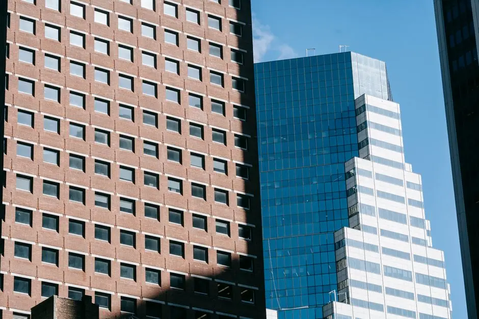 From below of multistory residential building located near modern skyscraper in megapolis under blue sky