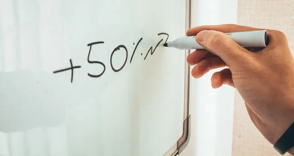 Crop anonymous male teacher writing math formulas on whiteboard during lessons in modern classroom