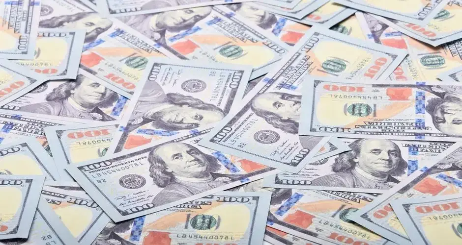 Close-up view of scattered US hundred dollar bills, showcasing paper currency.