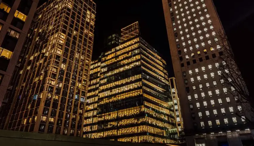 A stunning view of London's modern skyscrapers illuminated against the night sky in a vibrant urban setting.