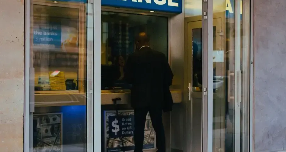 A businessman changes money at a currency exchange counter indoors.