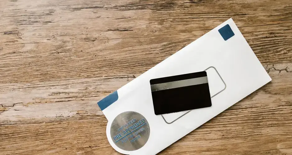 A blank credit card with a pre-approved envelope on a wooden table, showcasing financial opportunities.