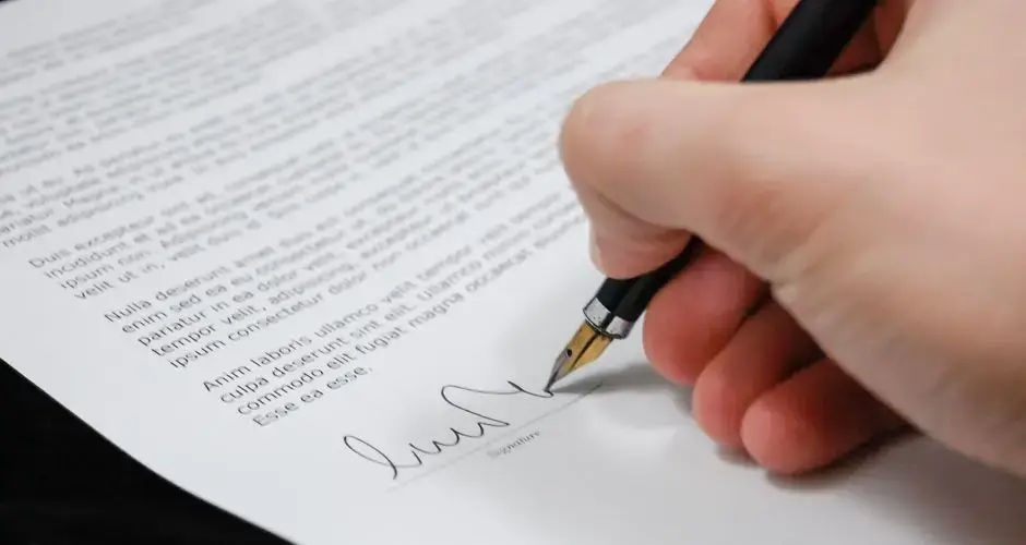 Close-up of a hand signing a legal document with a fountain pen, symbolizing signature and agreement.