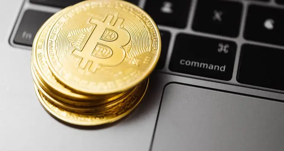 Close-up of gold bitcoin coins on a laptop keyboard, symbolizing digital currency and technology.