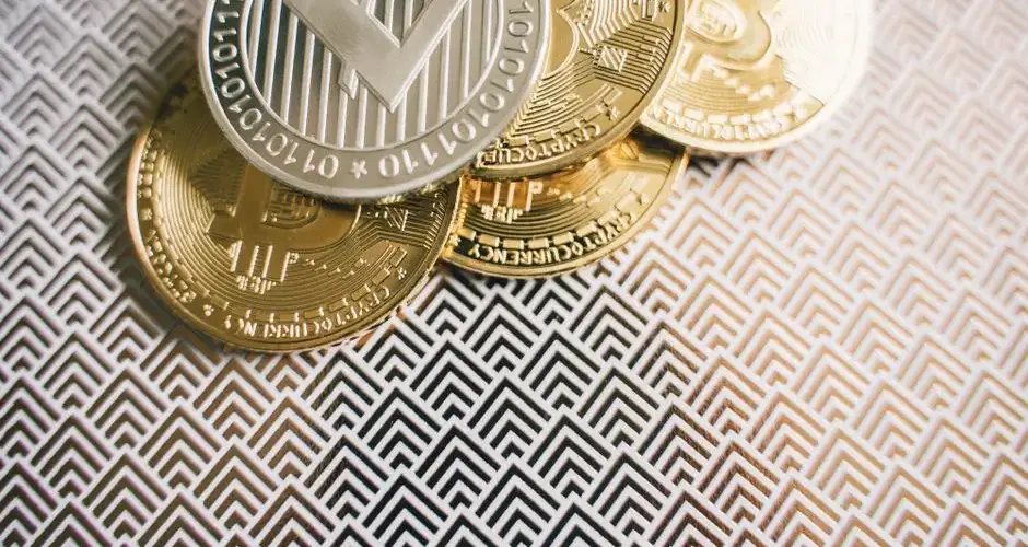 Close-up image of Bitcoin and Litecoin coins on geometric patterned surface.