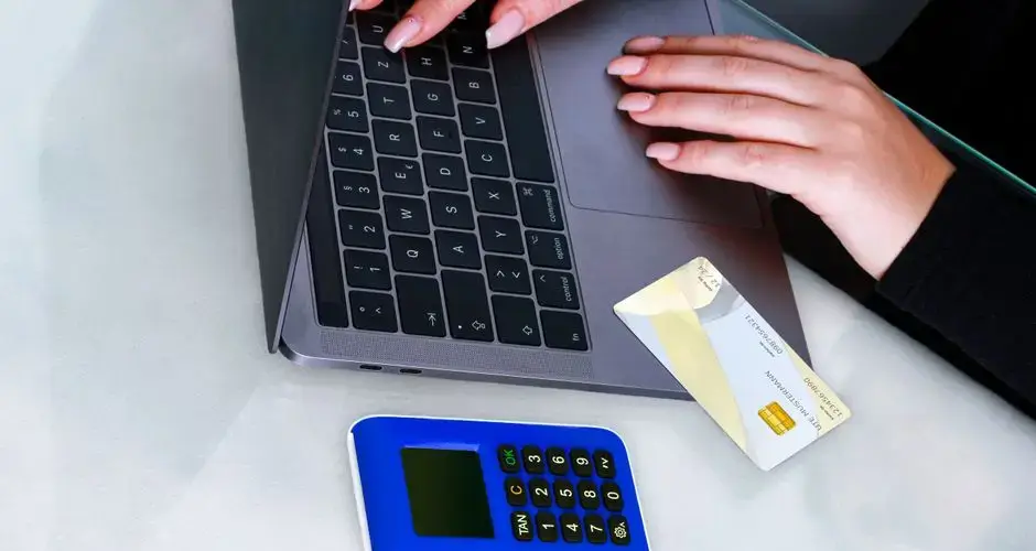 Hands using laptop with card reader for secure online payment. Technology-driven financial transaction.