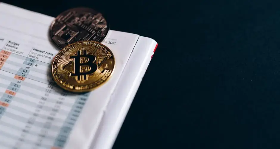 Close-up of Bitcoin coins on a financial report on a dark surface.