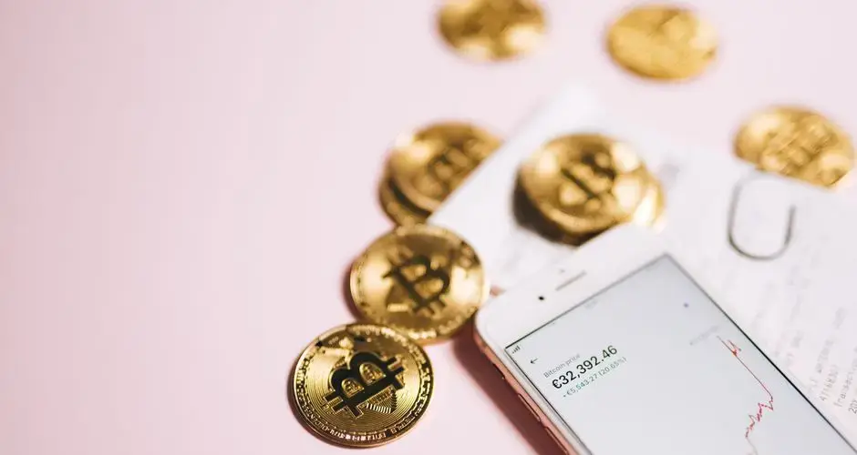 Bitcoin coins with a smartphone displaying financial data, symbolizing cryptocurrency and digital investments.
