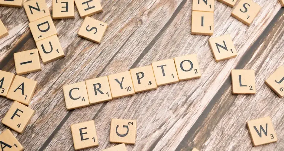 Wooden letter tiles spelling 'Crypto' creatively arranged on a rustic wood surface.