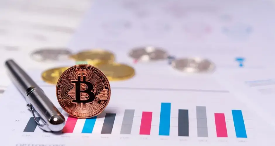 Close-up of a Bitcoin coin placed on financial charts with a pen, symbolizing cryptocurrency and economic analysis.