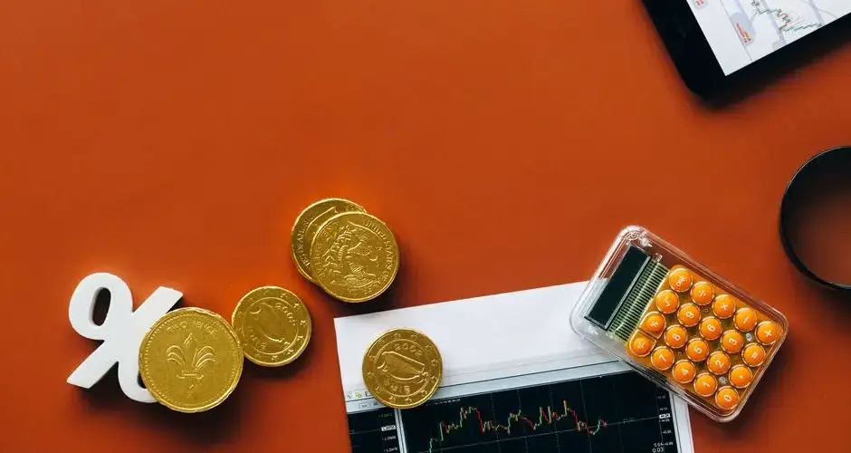 Flat lay showing coins, calculator, and charts on a red background for financial analysis and business concepts.