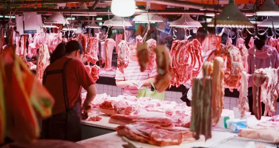 A vibrant scene capturing customers and vendors in a bustling indoor meat market.