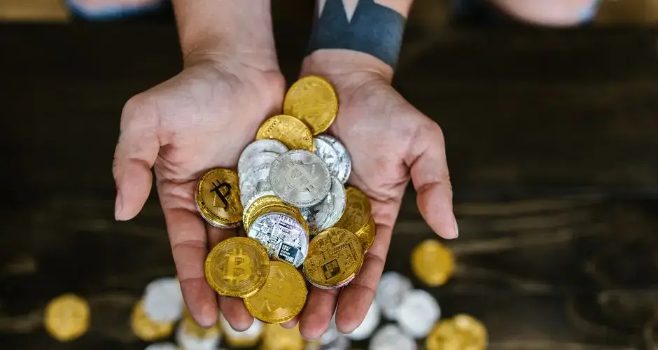 High angle of hands holding gold and silver cryptocurrency coins, symbolizing digital wealth.