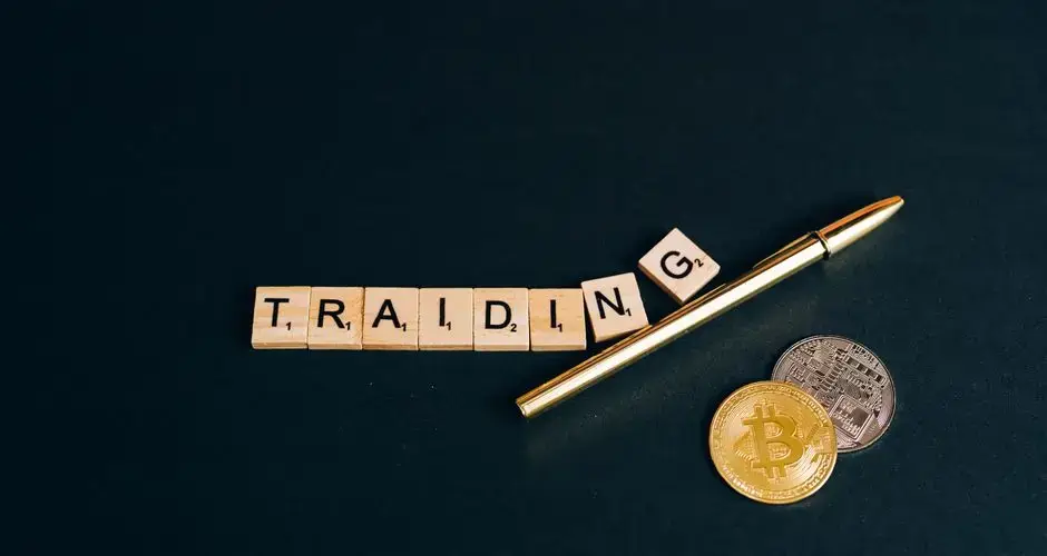 Bitcoin and trading concept shown with coins, pen, and letter tiles on a dark background.
