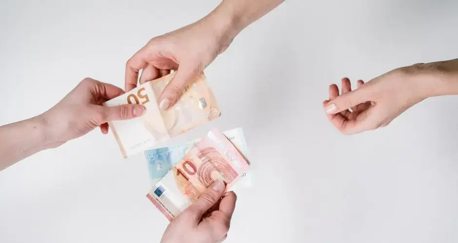 Close-up of hands exchanging euro banknotes, symbolizing currency trade and financial transactions.
