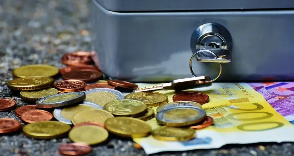 Close-up of a secure cash box with euro coins and banknotes, symbolizing wealth and financial security.