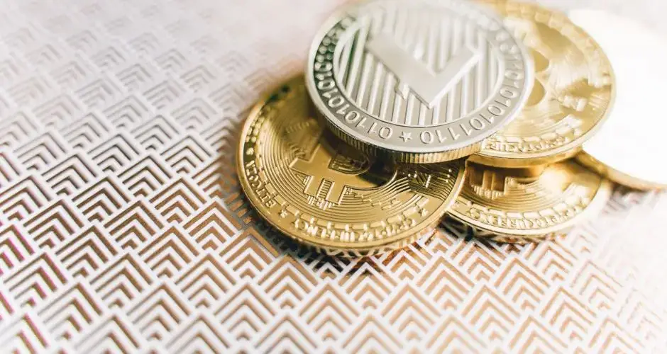 Stack of Bitcoin and Litecoin coins on a geometric textured surface, symbolizing digital finance.
