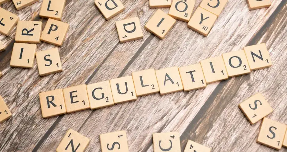 Wooden letter tiles spelling 'Regulation' on a textured wood background, conveying themes of compliance and structure.