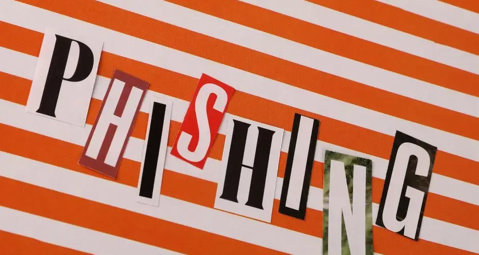 Conceptual image of the word 'Phishing' using cut-out letters on an orange striped background.