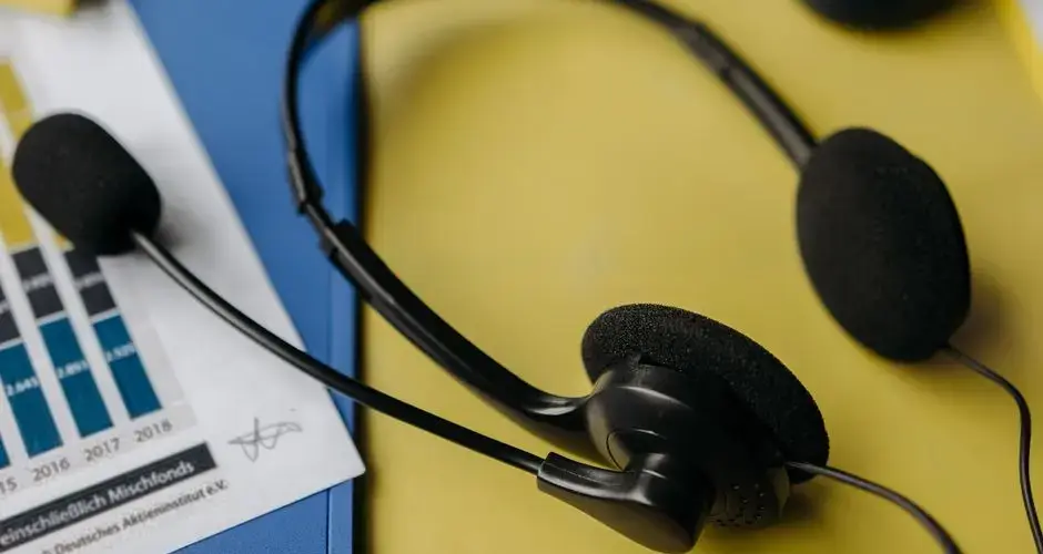 Close-up of a headset on a workspace desk with graphs and office supplies.