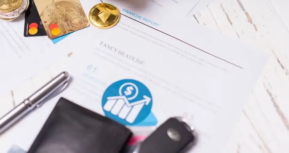 Close-up of financial documents, credit cards, coins, and a pen on a wooden desk.
