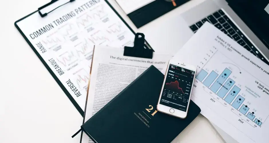High-angle shot of a stock trading desk with charts, graphs, and a smartphone displaying market trends.