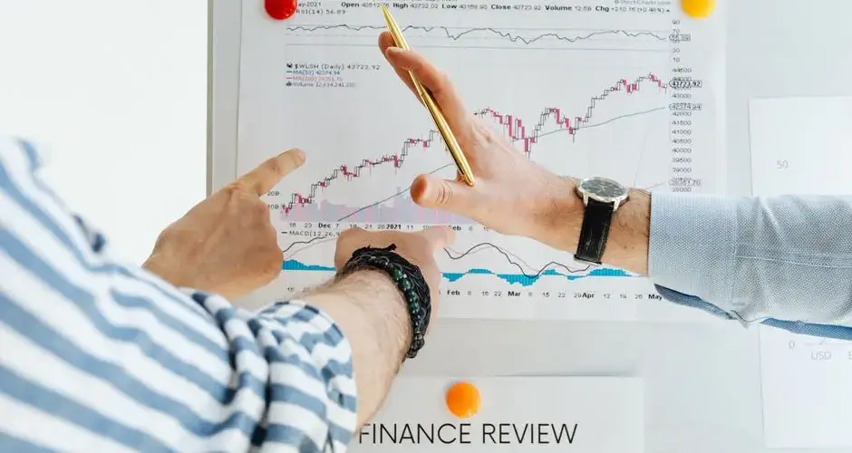 Professionals analyzing financial charts at a whiteboard meeting.