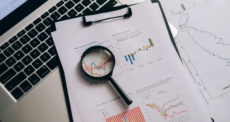 Overhead view of financial charts, laptop, and magnifying glass, ideal for business analysis themes.