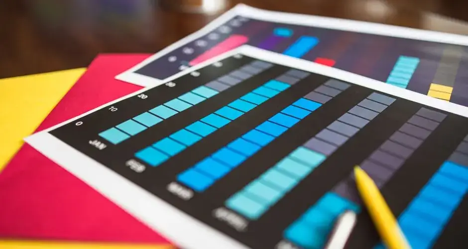 Close-up of colorful financial charts and a pencil on a wooden desk.