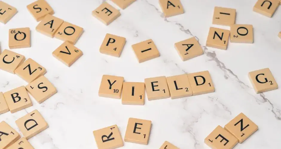 Scrabble tiles forming the word 'YIELD' on a marble surface, symbolizing finance and investment.