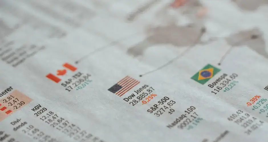 Detailed close-up of a newspaper displaying global financial market statistics and country flags.