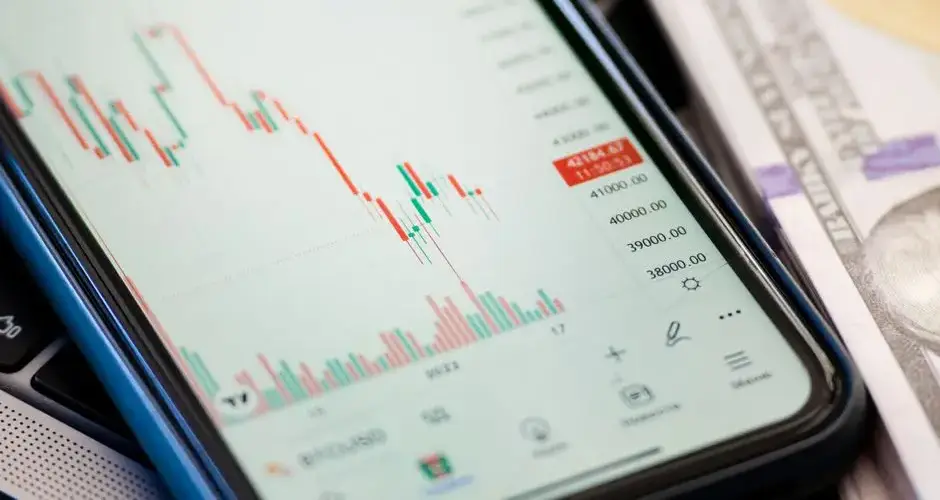 Detailed view of stock market data on a smartphone with US dollars in the background, illustrating trading.