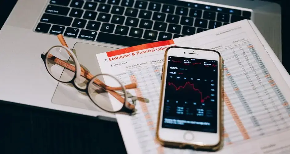 A detailed look at financial tools including a smartphone and laptop for stock analysis.