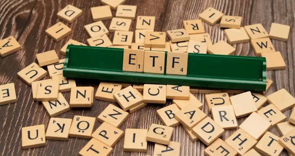 Wooden tiles spelling ETF on a game holder, representing investment themes.